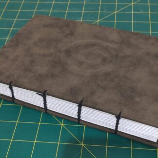 A hard-cover, hand-bound notebook. The cover is bound with pleather with a pokeball symbol embossed on it.