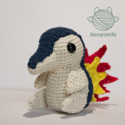 Front view of a Cyndaquil crochet plushie, made from dark blue, light yellow, red, and yellow yarn.