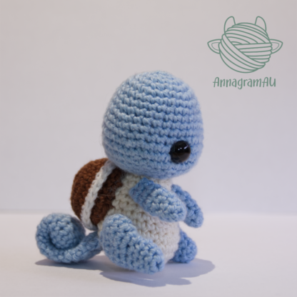 Side view of a Squirtle crochet plushie, made from light blue, light yellow, brown, and white yarn.