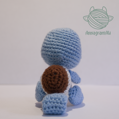 Back view of a Squirtle crochet plushie made out of light blue, brown and white yarn.